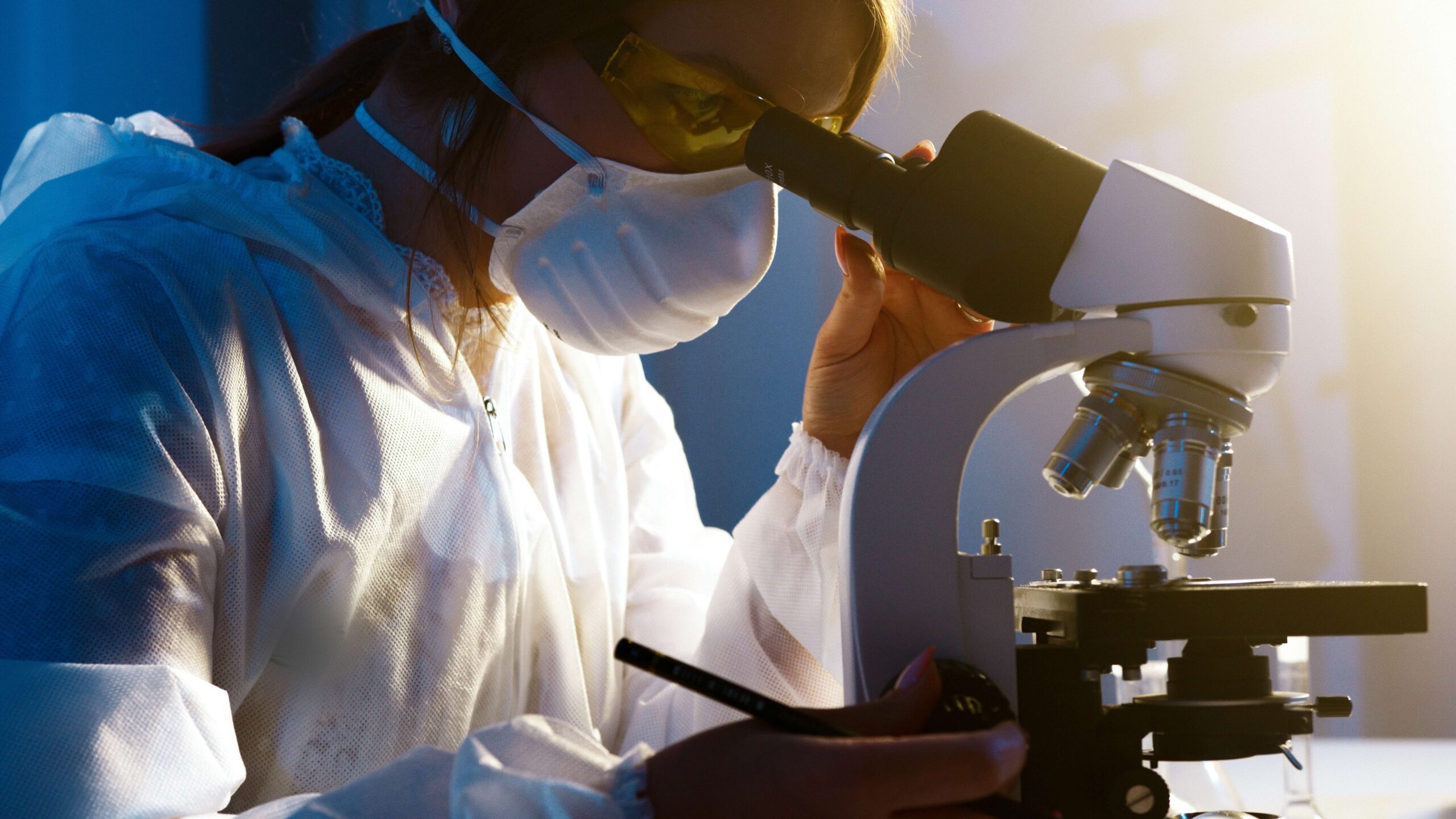 Žena v laboratoři se dívá do mikroskopu